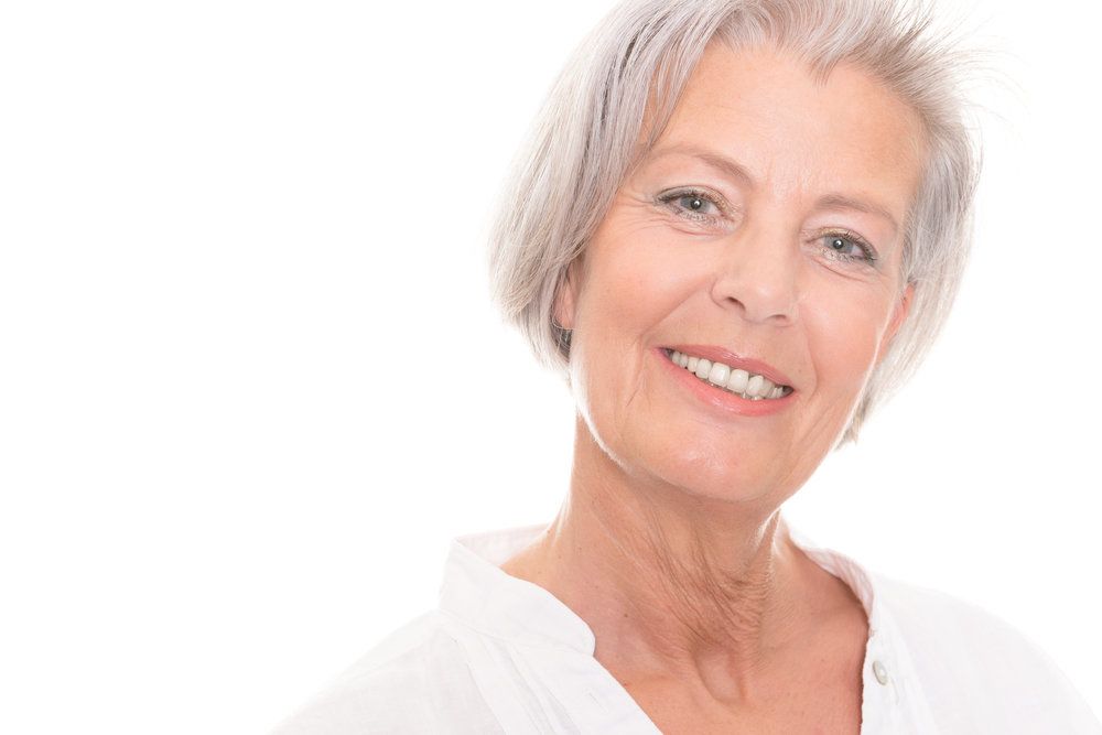 Mature woman smiling, white background.