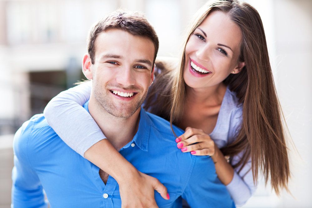 Smiling couple with man piggybacking woman