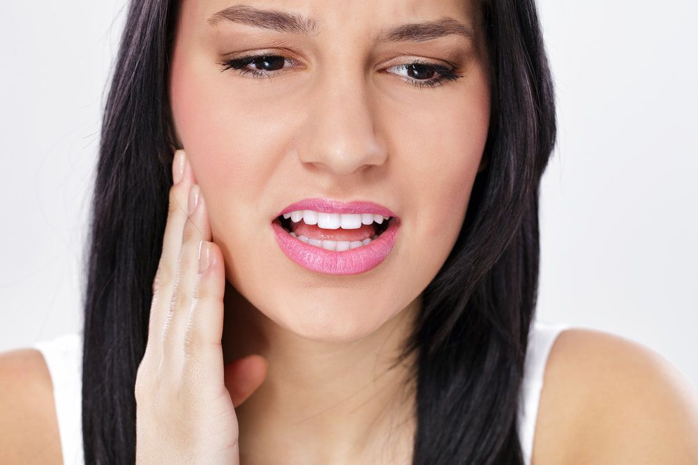 Grimacing woman holding jaw in pain